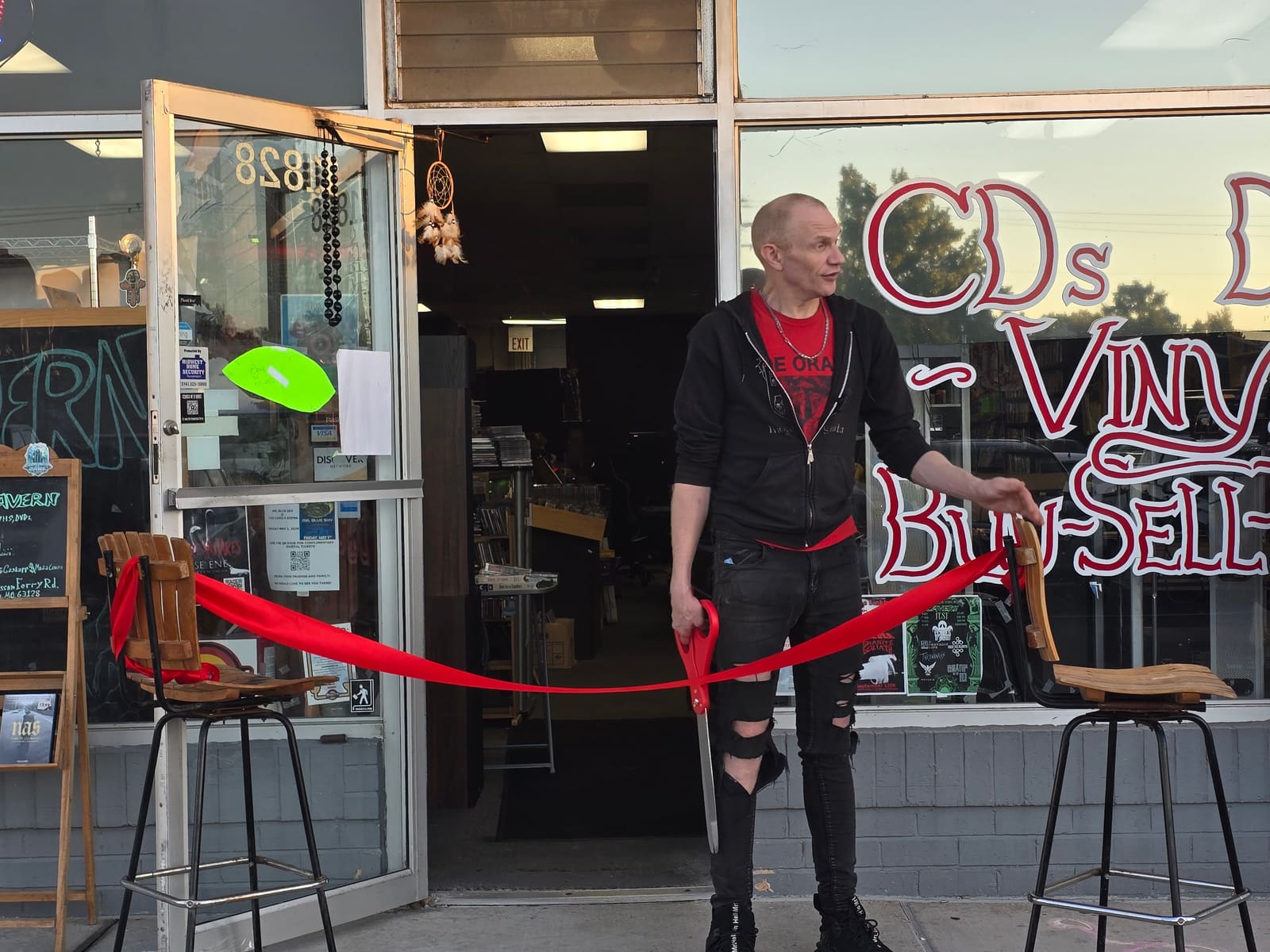 The ribbon cutting outside Media Cavern, with oversized scissors and a red ribbon