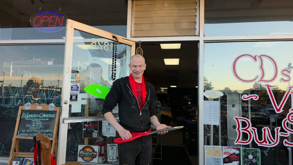 Smiling with the ribbon-cutting scissors at the Media Cavern door