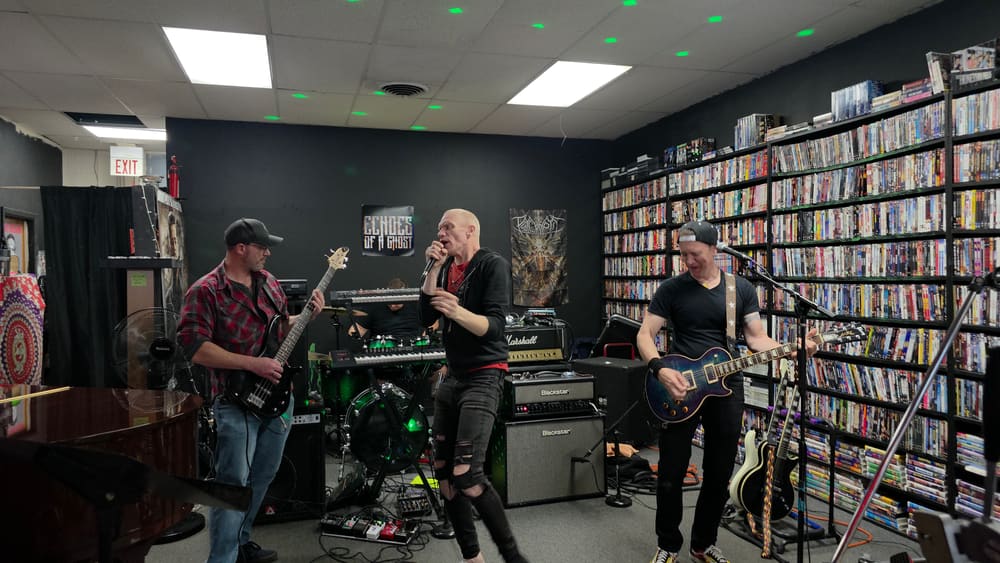 A band performing inside Media Cavern in front of shelves of movies