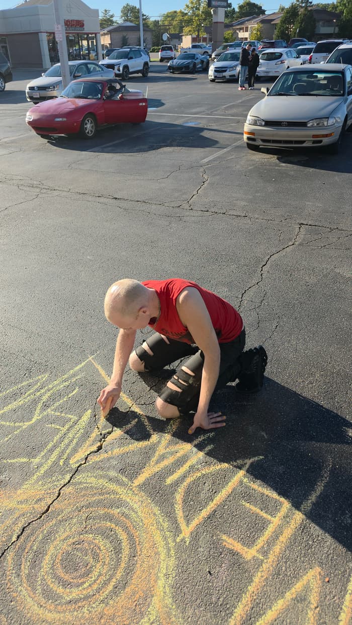 Drawing in chalk on the parking lot outside Media Cavern
